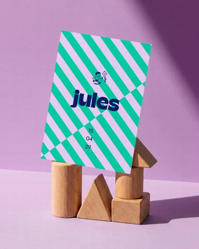 Jules geboortekaartje met diagonale strepen in mintgroen en lila, een jongetje met een vlieger en de naam groot in rond inktblauw
