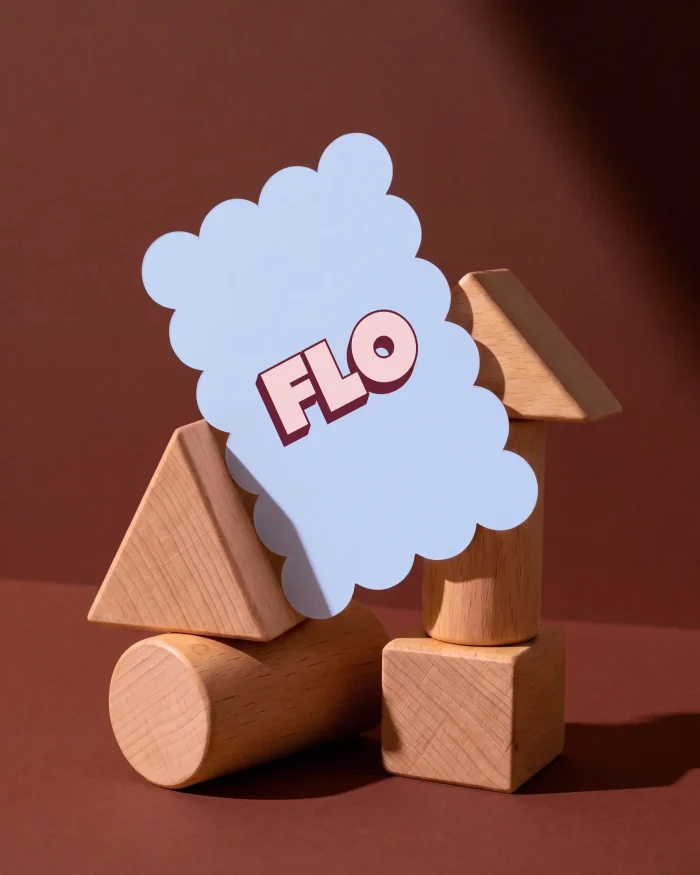 Flo geboortekaartje in ijsblauw met golvende rand en de naam in dikke roze letters met een bordeauxrode 3D-schaduw