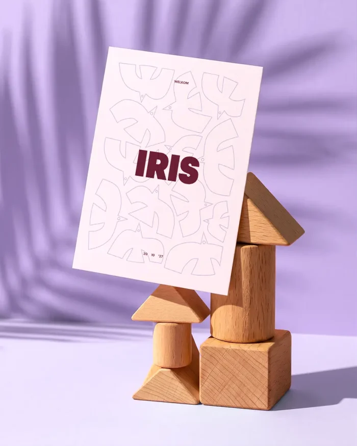 Iris geboortekaartje in zacht lila met een subtiel patroon van gestileerde vogeltjes en de naam in vette bordeauxrode letters